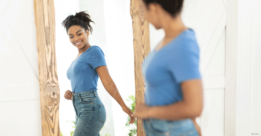 Woman in Des Moines admiring results in the mirror from her CoolSculpting® Elite treatment
